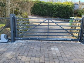 A metal field type gate with automation on a block paved driveway